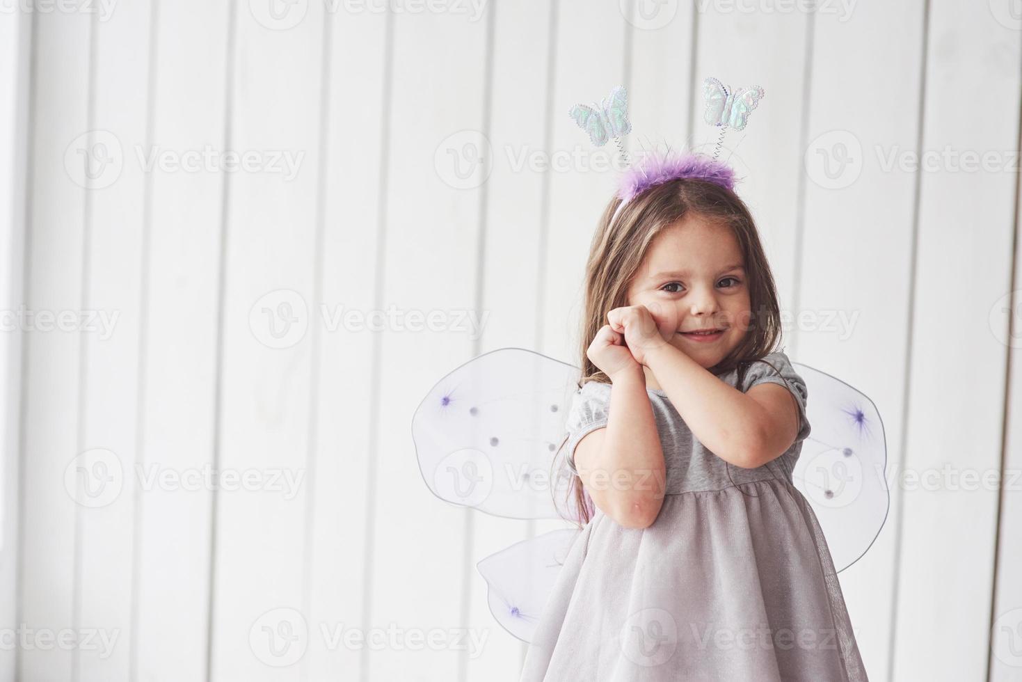 Shy and holding hands to the face. Beautiful little girl with fairy costume having fun posing for the pictures photo