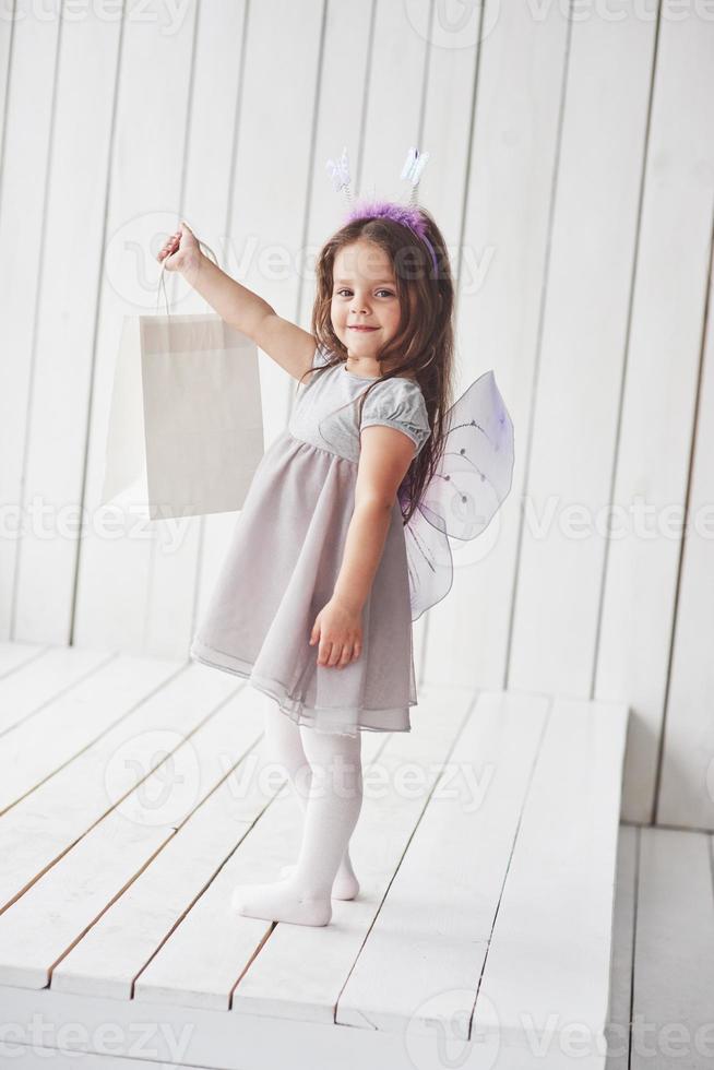 Holding the package. Beautiful little girl with fairy costume having fun posing for the pictures photo