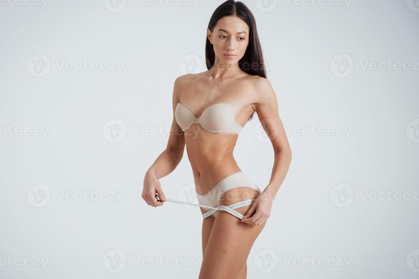 hermosa morena en ropa interior sosteniendo la línea en las manos alrededor de las piernas foto