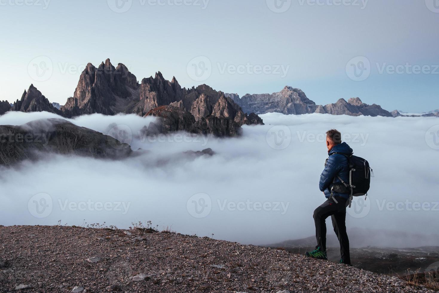 Looking at mighty power of nature. Tired traveler in process of capturing the mountain, taking a break after long distance walking and climbing at the top photo