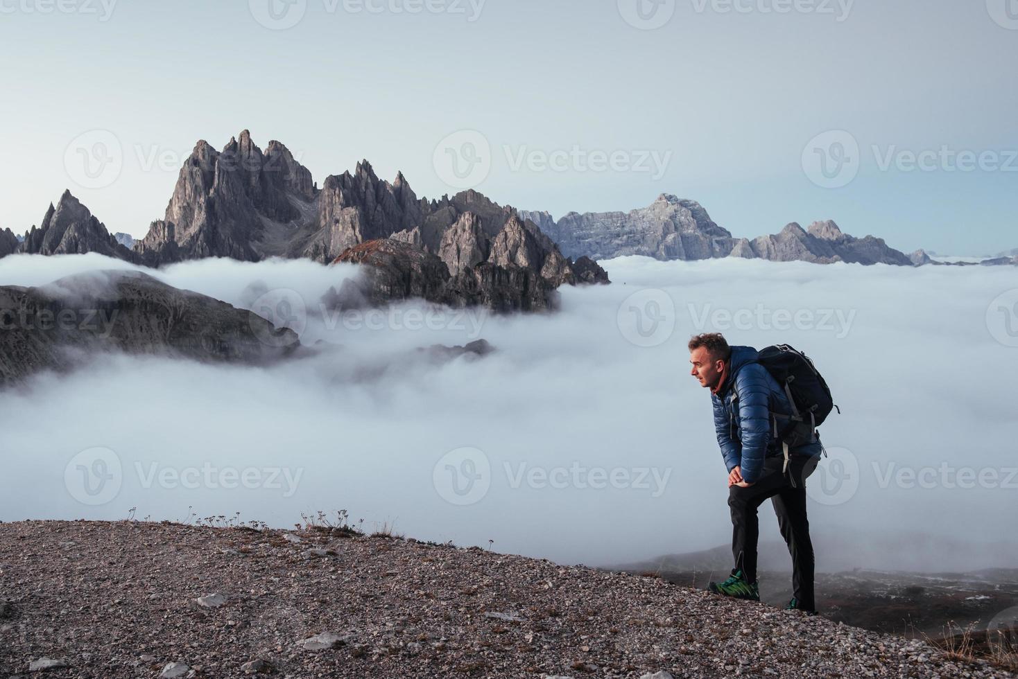 Viajero cansado en proceso de capturar la montaña, tomando un descanso después de una caminata larga y escalando en la cima. foto