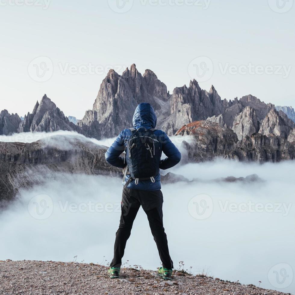 disfrutando el momento. chico parado en la colina y mirando las grandes montañas lejanas en la niebla foto