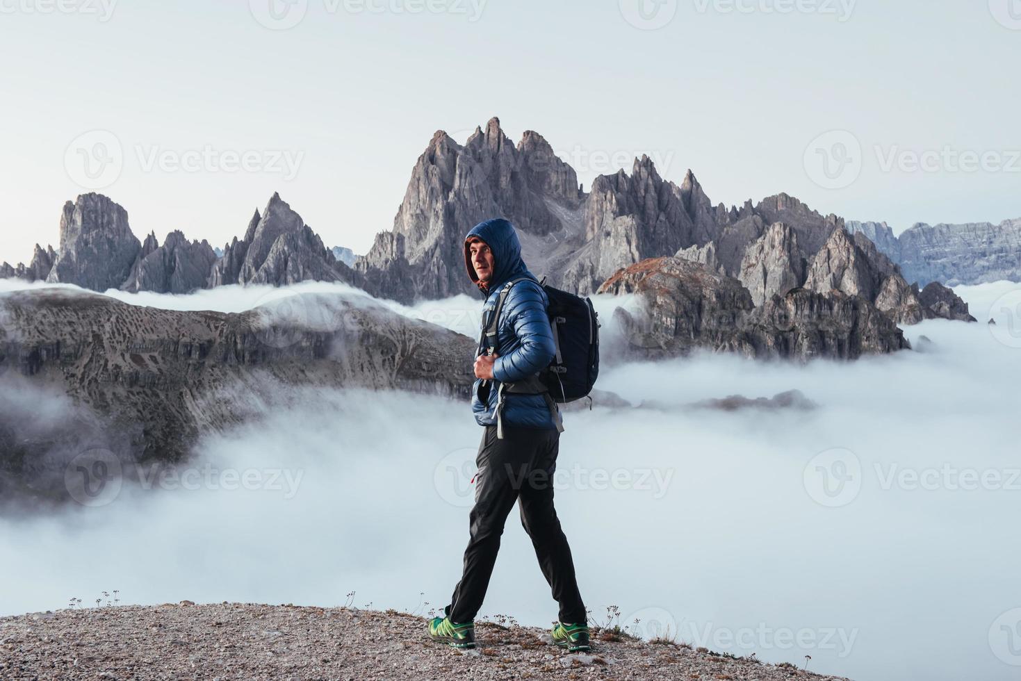 Man turned his head around and looking into the camera on the beautiful mountain background full of fog photo