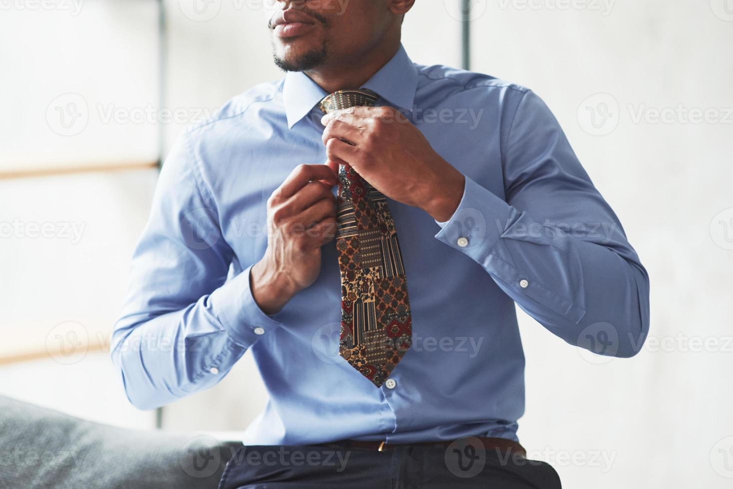 Almost ready. Photo of black stylish man getting wearing clothes and preparing for the work