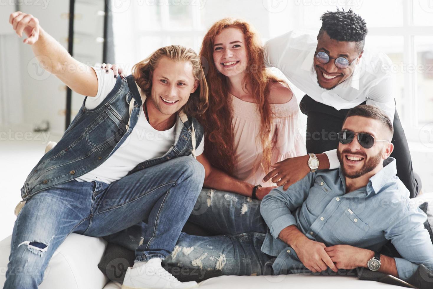 Office friends have cheerful time sitting and laying on the white sofa photo