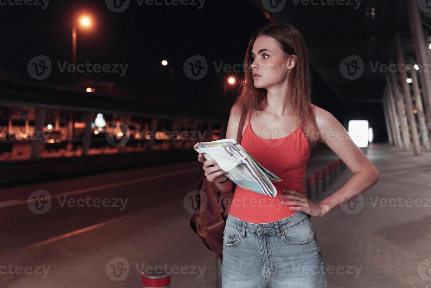 Standing at night time with map in the hands and waiting for the taxi photo