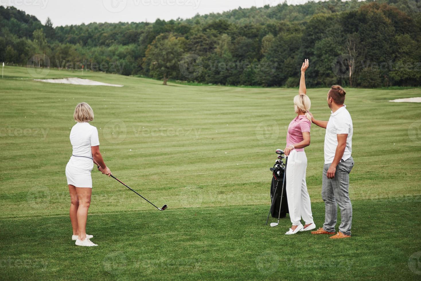 grupo de elegantes amigos en el campo de golf aprende a jugar un nuevo juego foto