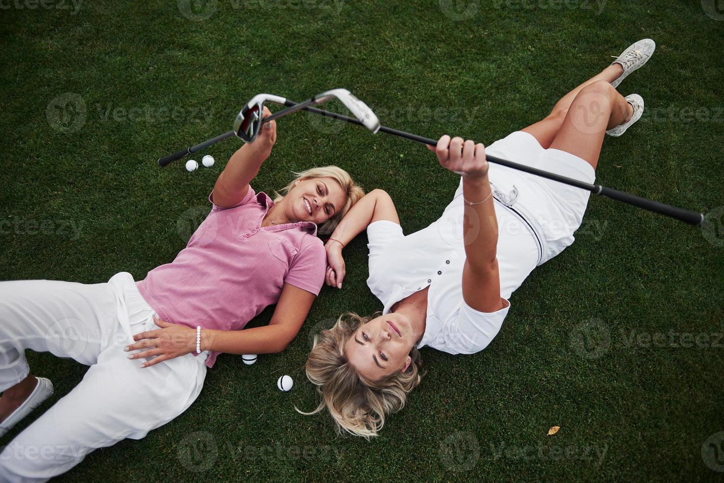 Two girls lie on the golf course and relax after the game photo