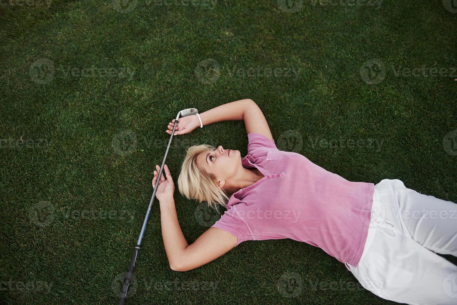 la niña se acuesta en el campo de golf y se relaja después del juego foto