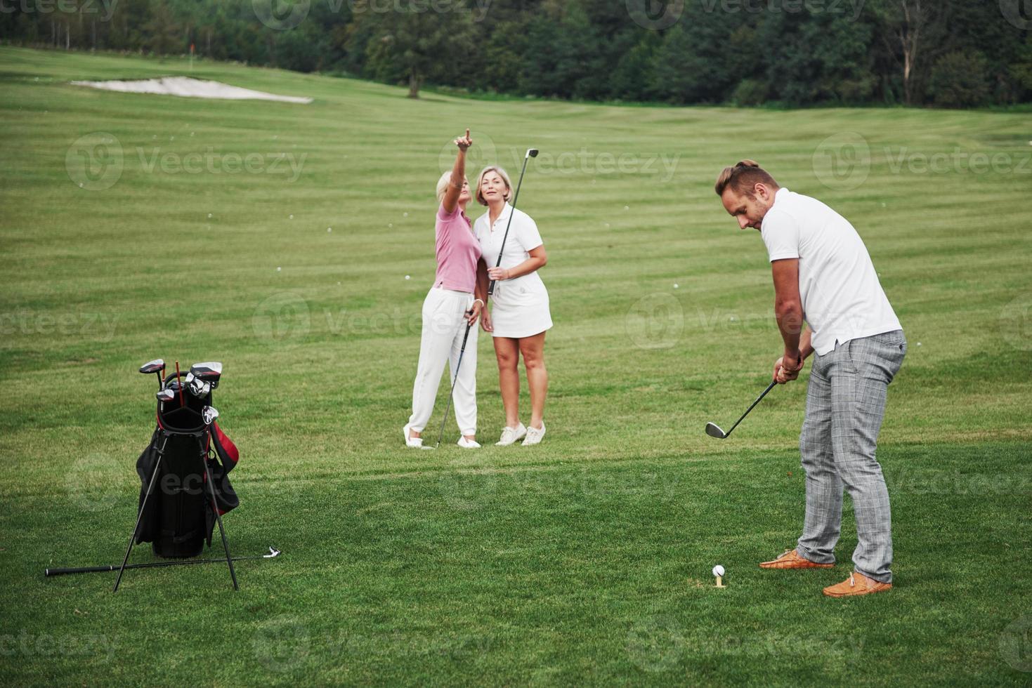 grupo de elegantes amigos en el campo de golf aprende a jugar un nuevo juego foto