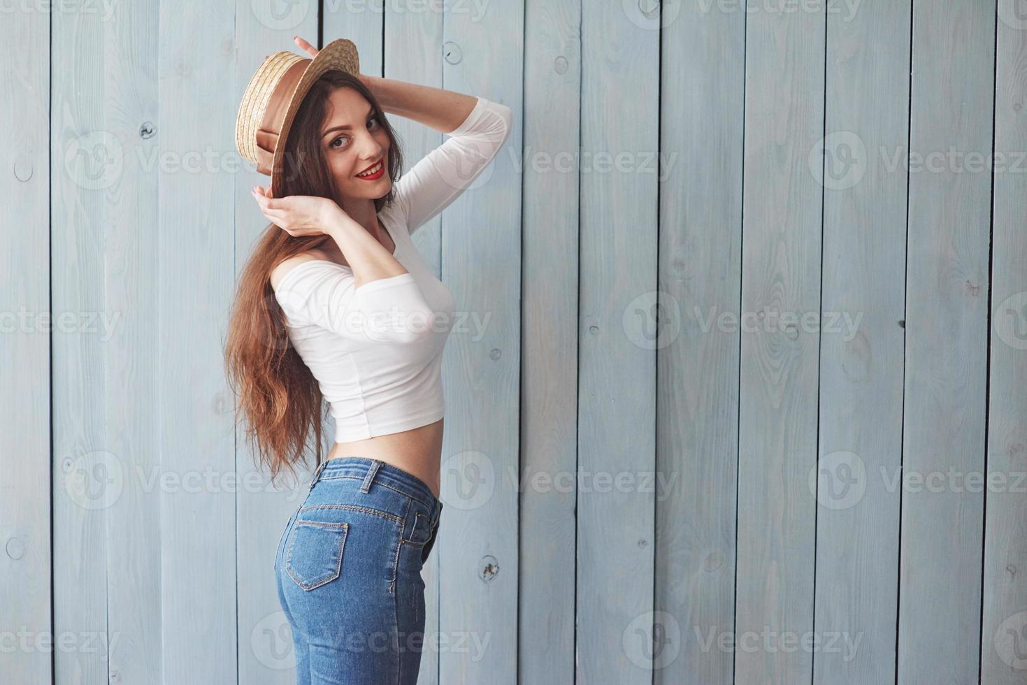 chica del sombrero se volvió de lado a la cámara. de pie en el fondo de madera foto