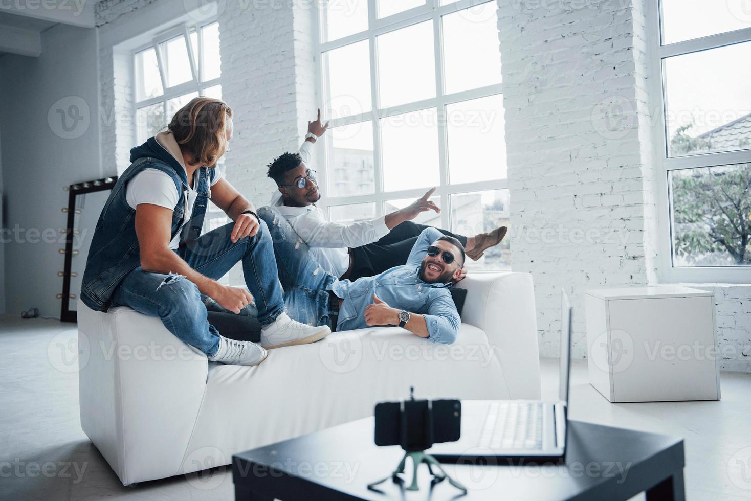 posando para la siguiente foto. los amigos han puesto el teléfono inteligente con temporizador automático en la mesa frente a ellos foto