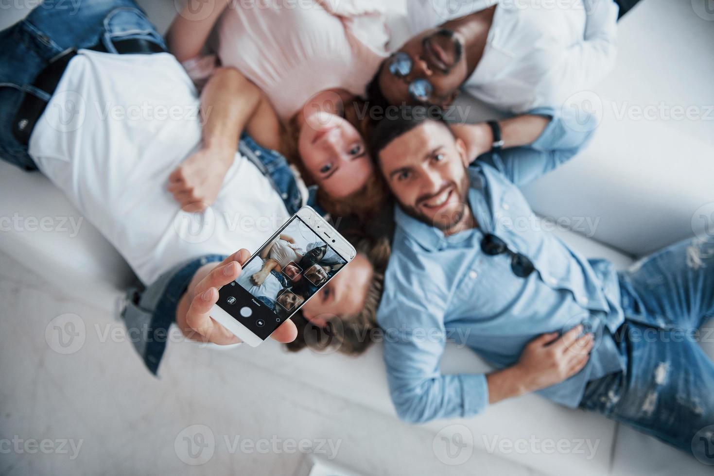 mire directamente a la cámara. Los jóvenes se acuestan y se toman una selfie con enfoque en el teléfono. foto