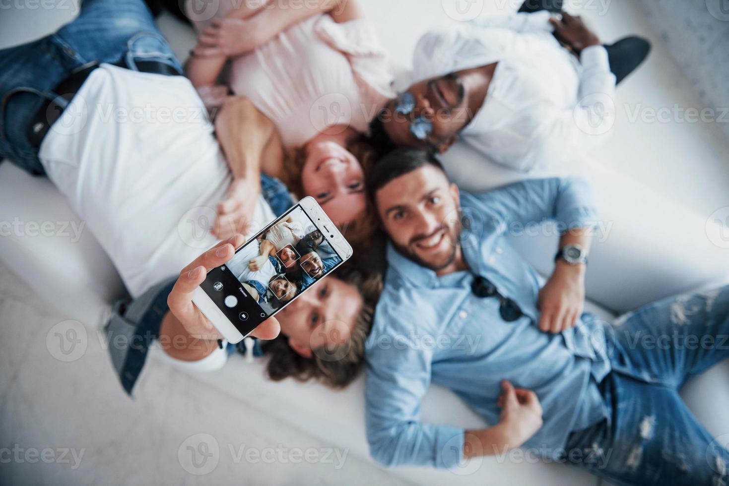 Sincere smiles. Young people laying down and take a selfie with focus on the phone photo