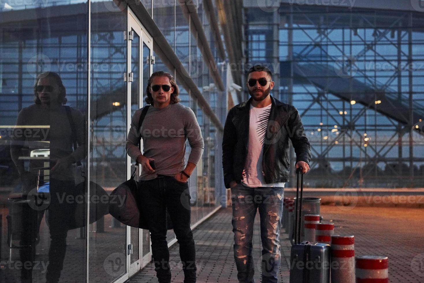 mirada tensa. dos elegantes amigos con gafas de sol se han conocido cerca del edificio del centro de negocios y caminando frente a la cámara foto