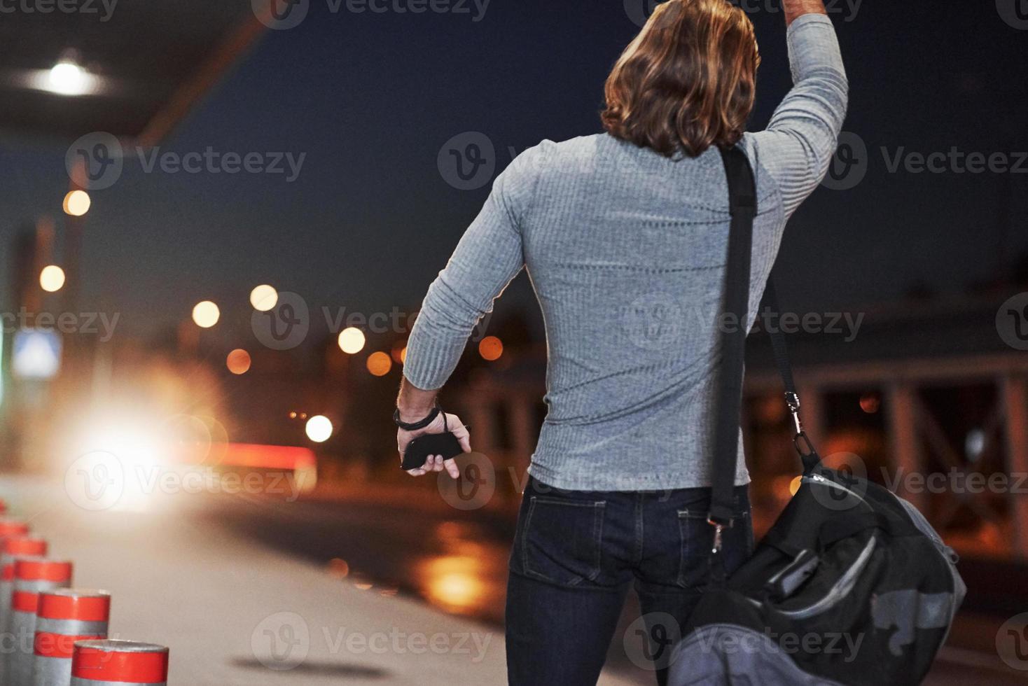 Pick me up please, I must be in airport right now. Young man with bag trying to stop the car because he's late photo