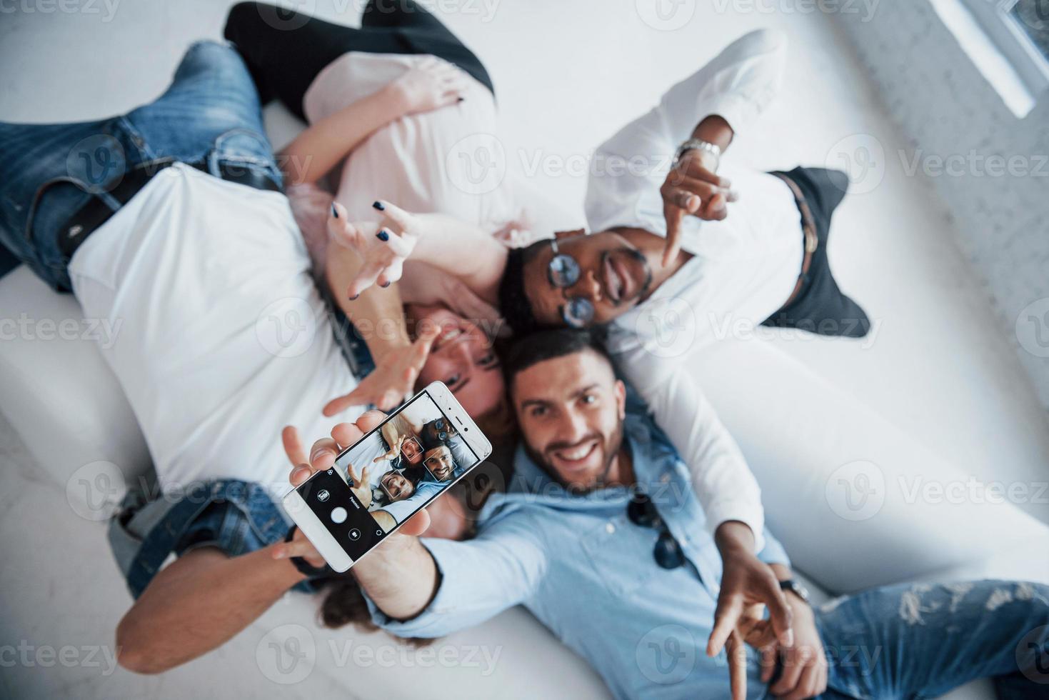 Young people laying down and take a selfie with focus on the phone photo