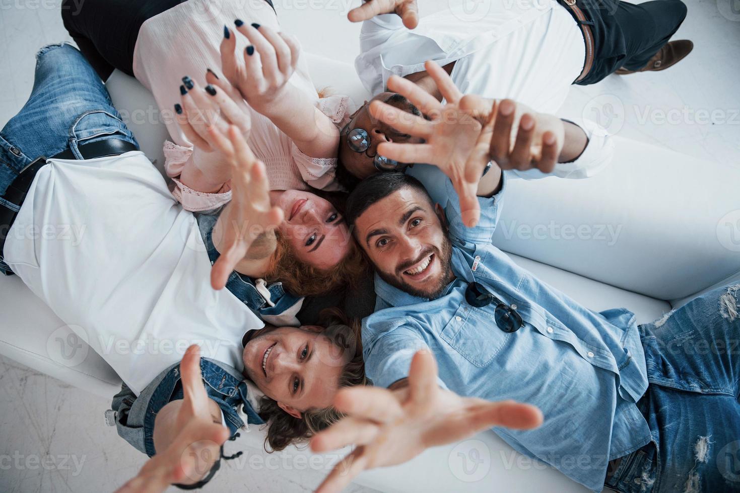 manos levantadas. jóvenes acostados y sonriendo a la cámara. foto