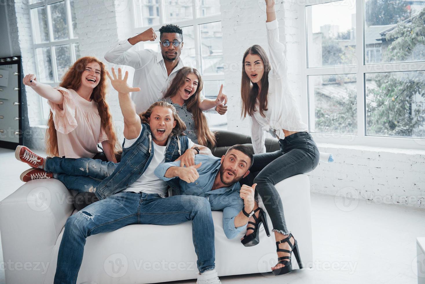 fiesta con camaradas. Alegres jóvenes amigos divirtiéndose y bebiendo en el interior blanco foto