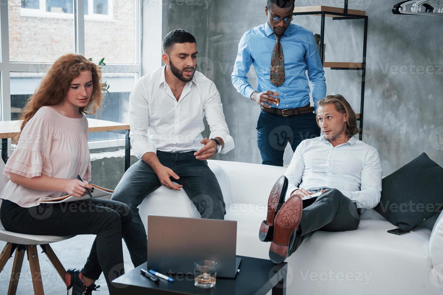 la libertad en el trabajo significa una mente despejada para nuevas ideas. Grupo de oficinistas multirraciales en ropa formal hablando de tareas y planes. foto