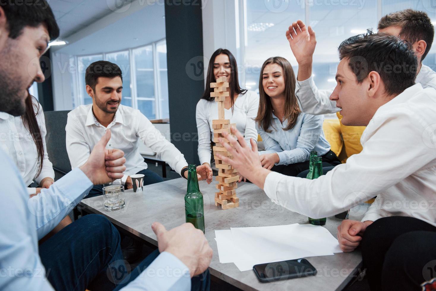 Tension is in the air. Celebrating successful deal. Young office workers sitting near the table with alcohol photo