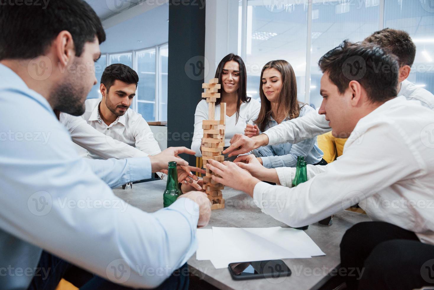 casi se cae. celebrando un trato exitoso. jóvenes trabajadores de oficina sentados cerca de la mesa con alcohol foto