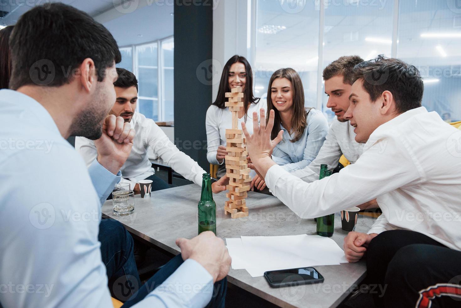divirtiéndose. celebrando un trato exitoso. jóvenes trabajadores de oficina sentados cerca de la mesa con alcohol foto