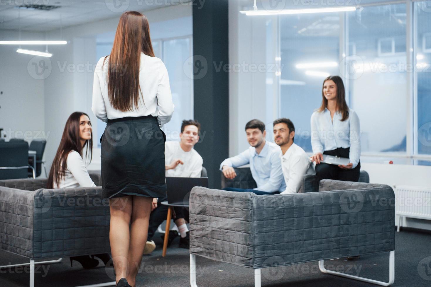 todo el mundo está feliz de verla. niña camina hacia los empleados que están sentados en el sofá y esperando foto