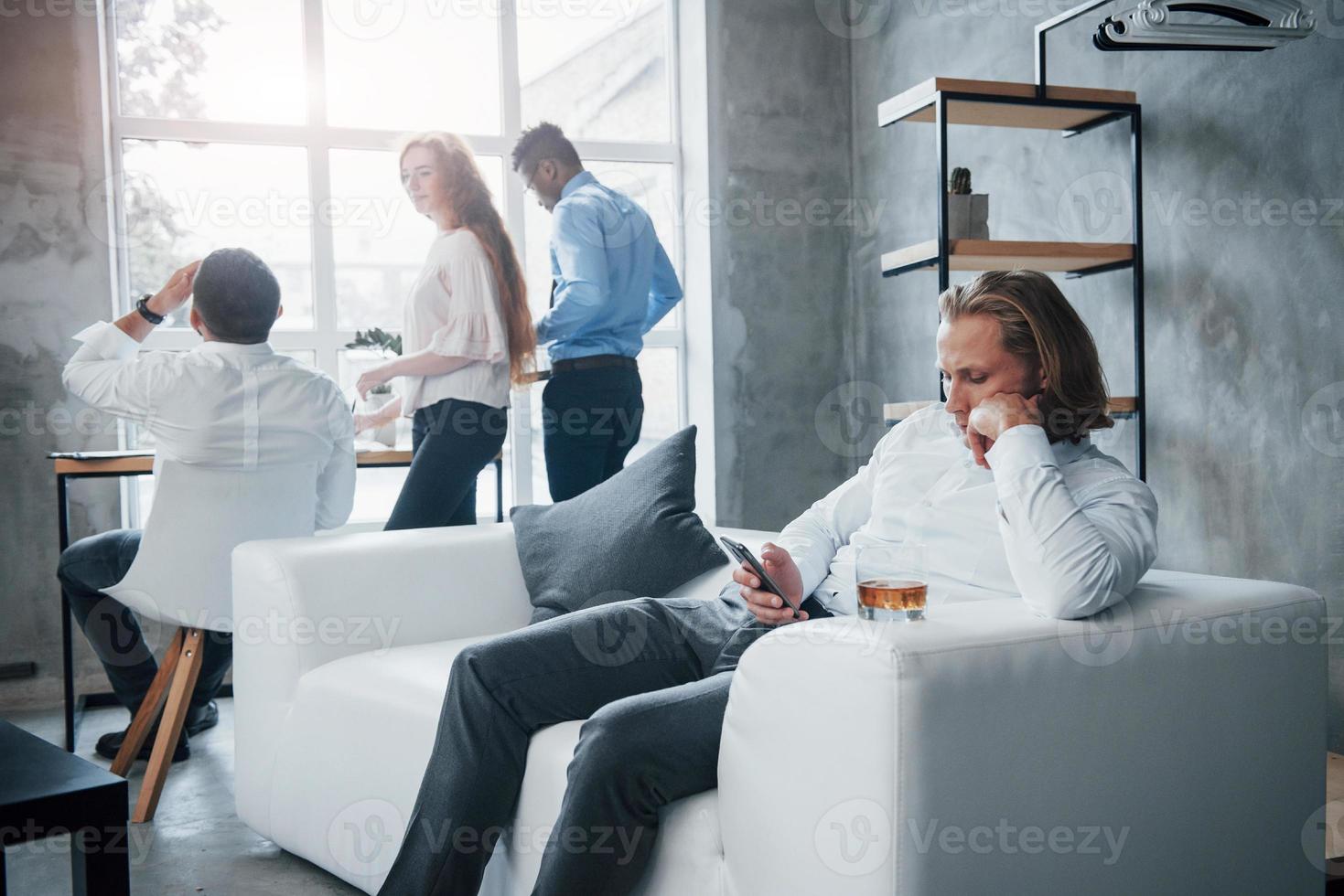 Man take the rest while others have discussion. Group of multiracial office workers in formal clothes talking about tasks and plans photo
