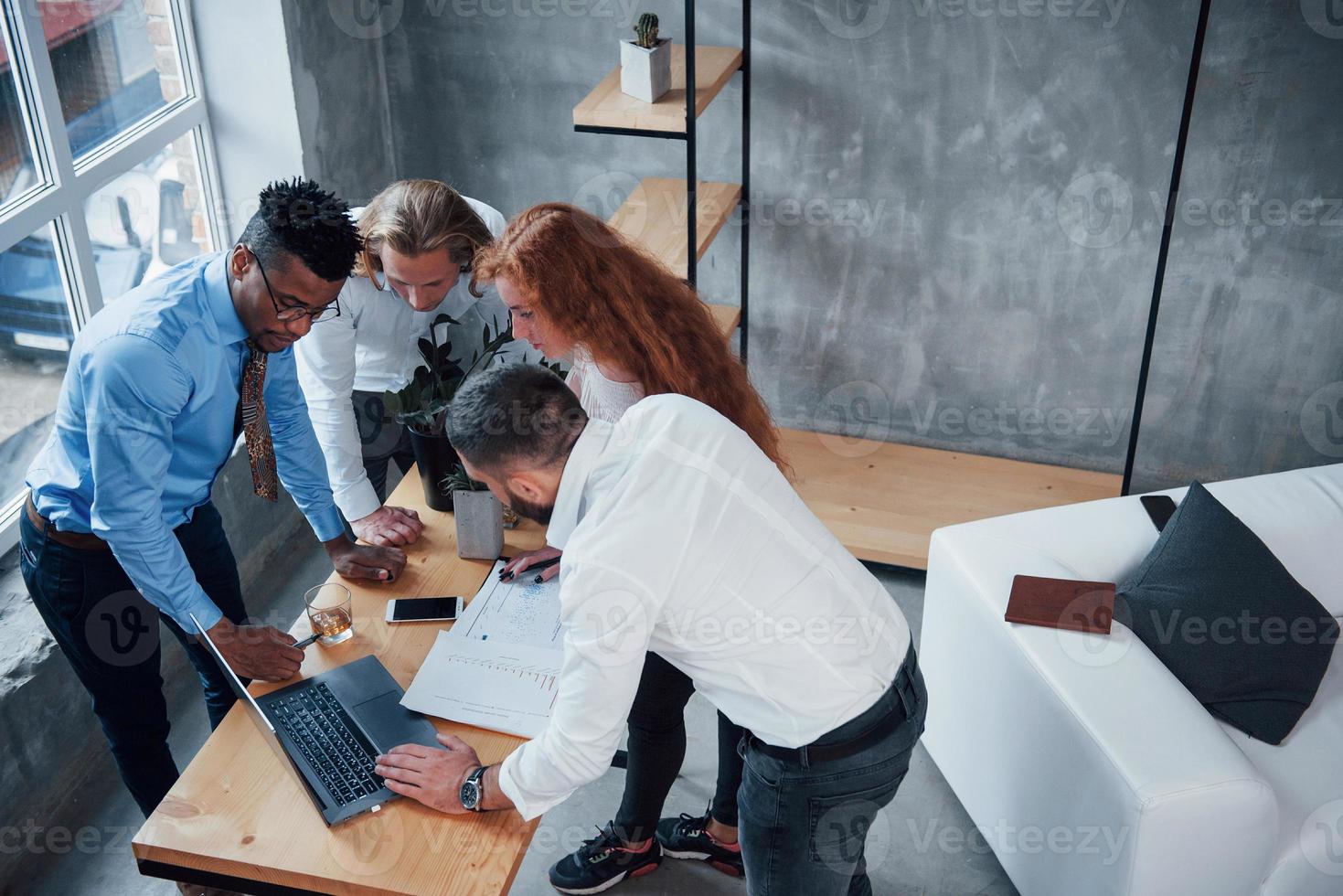 vista superior. Cuatro jóvenes empresarios que trabajan en el plan utilizan el cuaderno foto