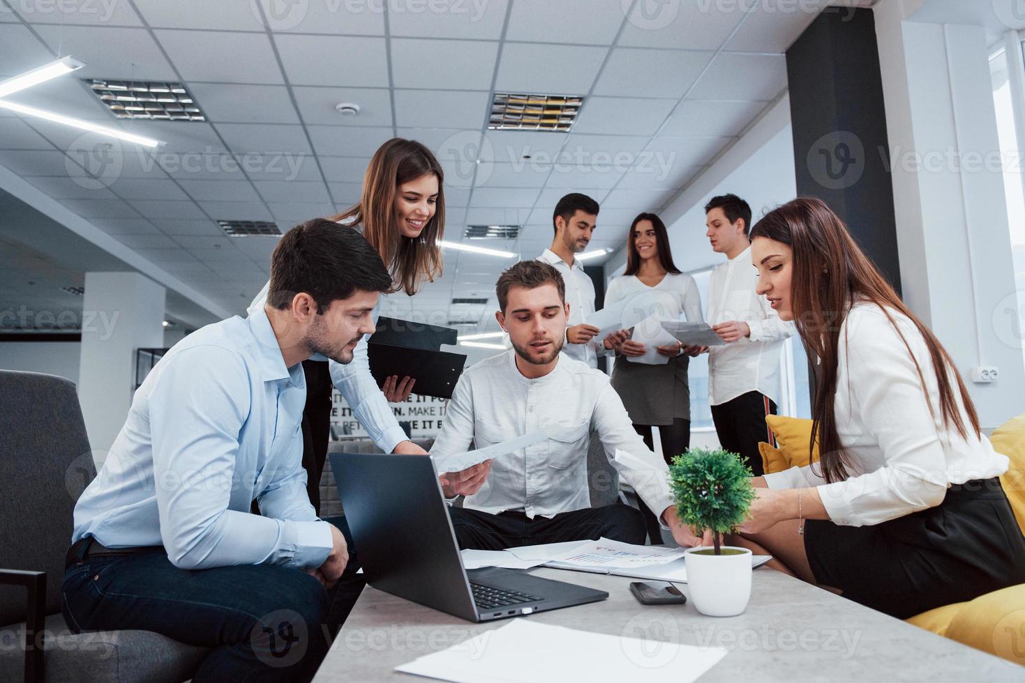 Making business plan. Group of young freelancers in the office have conversation and smiling photo