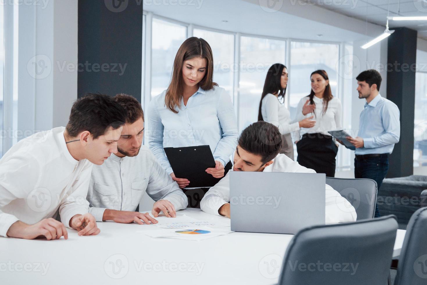 concentración en la planificación empresarial. Grupo de jóvenes autónomos en la oficina conversan y trabajan con documentos. foto