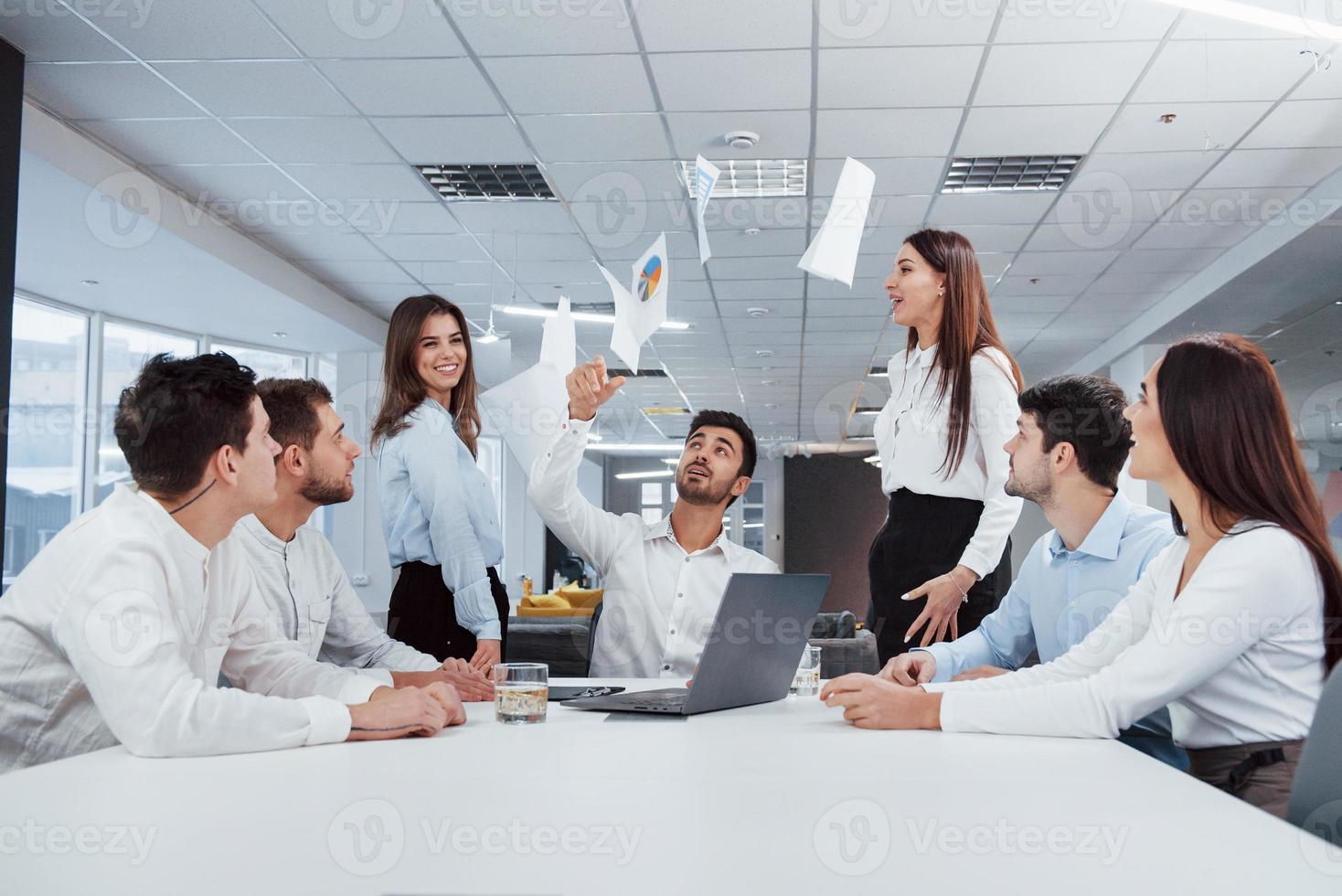 Celebrating by throwing papers up. Job is done. Group of office workers happy to hit their own records and being successful photo