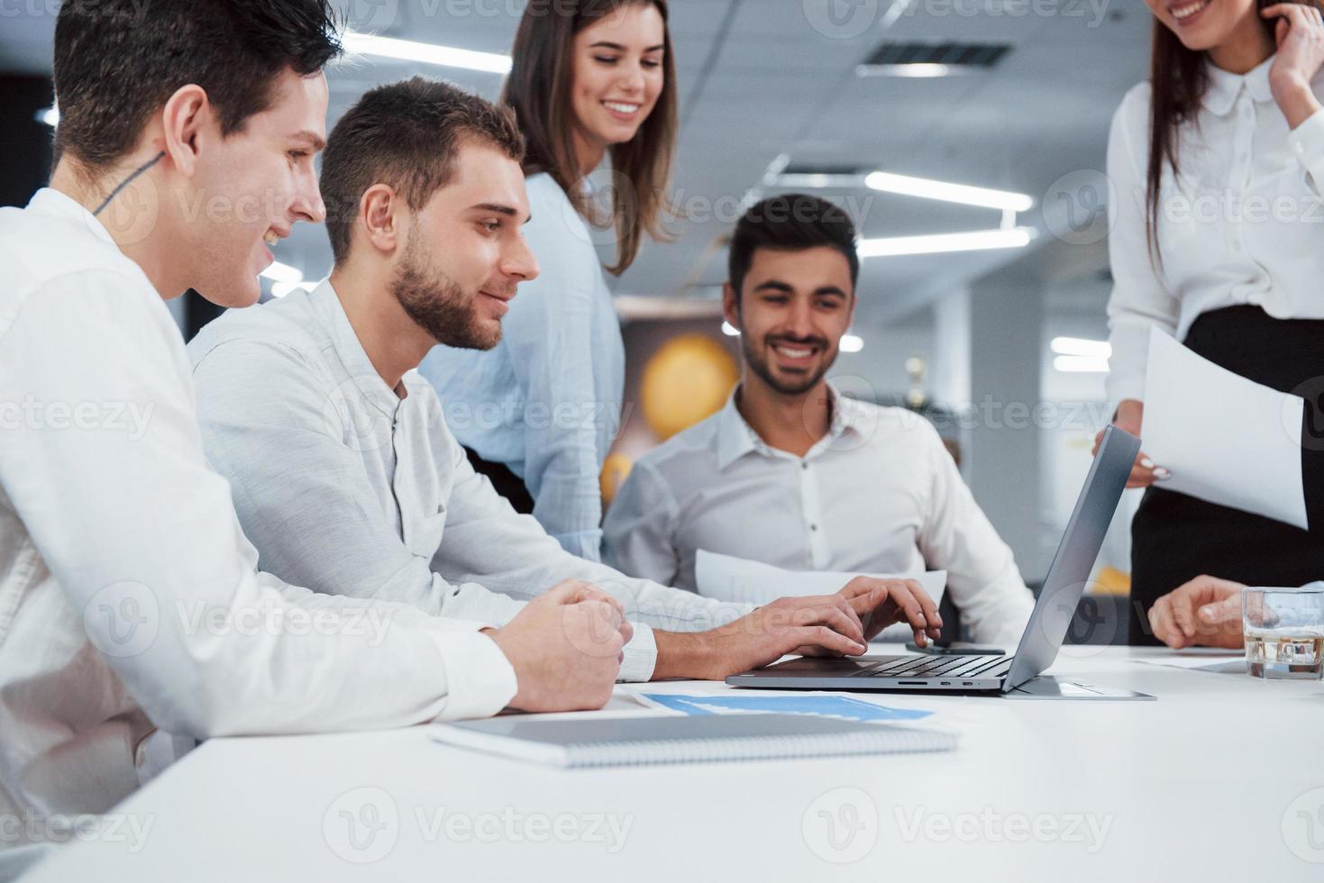 It looks like the project has exceeded all expectations. Group of young freelancers in the office have conversation and smiling photo