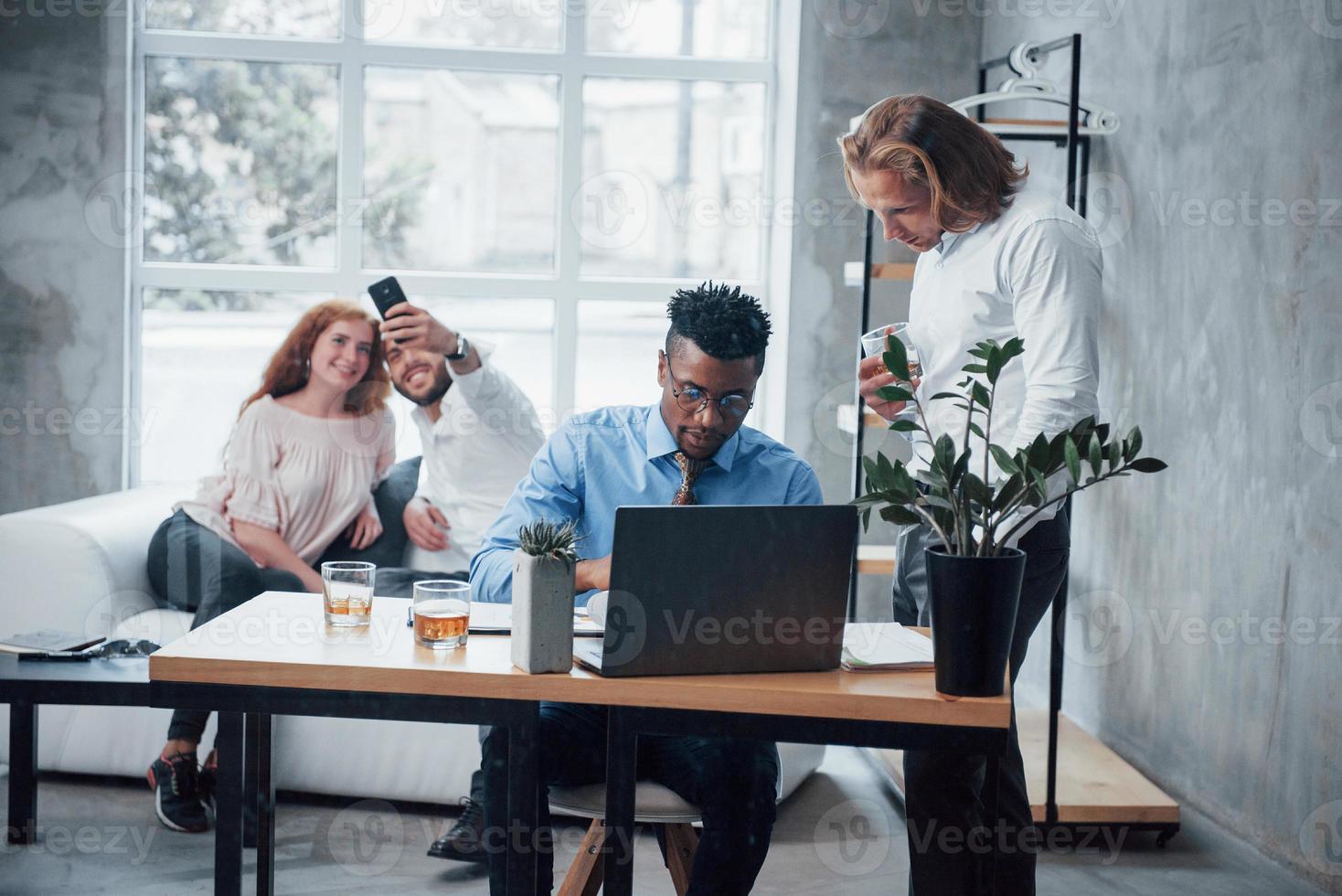 Selfie at background. Young business team working on a project with laptop on table and smiling photo