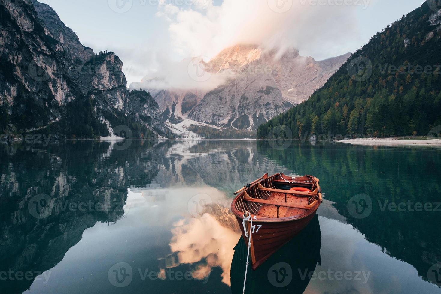 Such a lovely view. Wooden boat on the crystal lake with majestic mountain behind. Reflection in the water photo