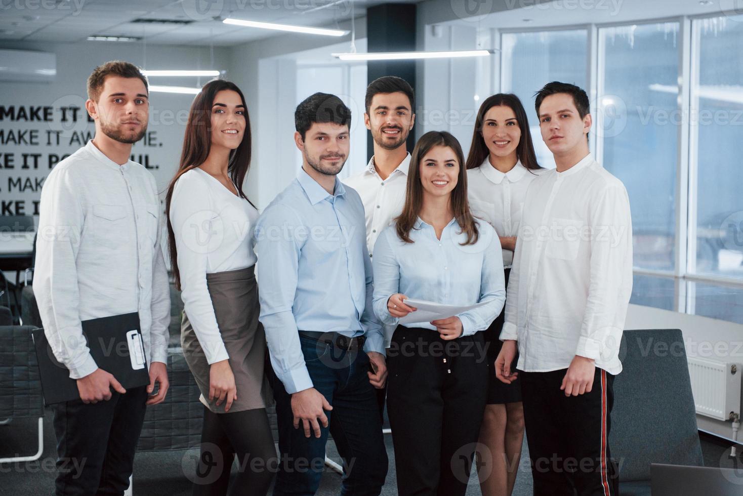 After work. Portrait of young team in classical clothes in the modern good lighted office photo