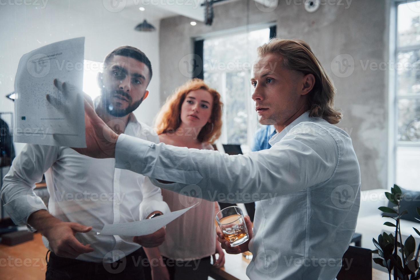 Price comparison. Young multiracial team in official wear at office looking at price list photo