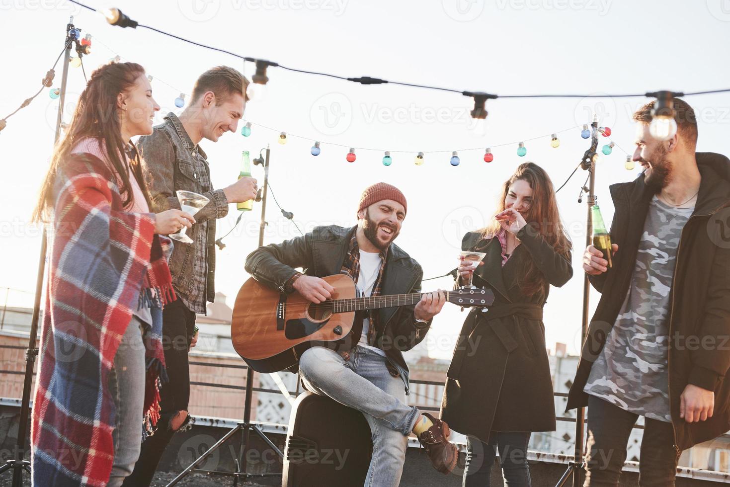 Everyone is happy. Five young friends have party with beer and guitar at the rooftop photo