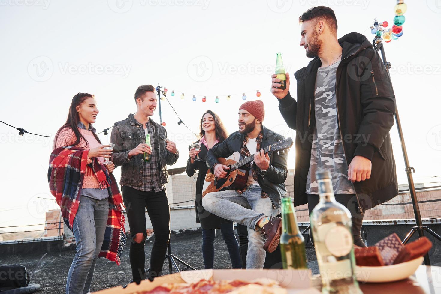 Having leisure. Table with food. Weekend on the rooftop with guitar, alcohol and pizza photo