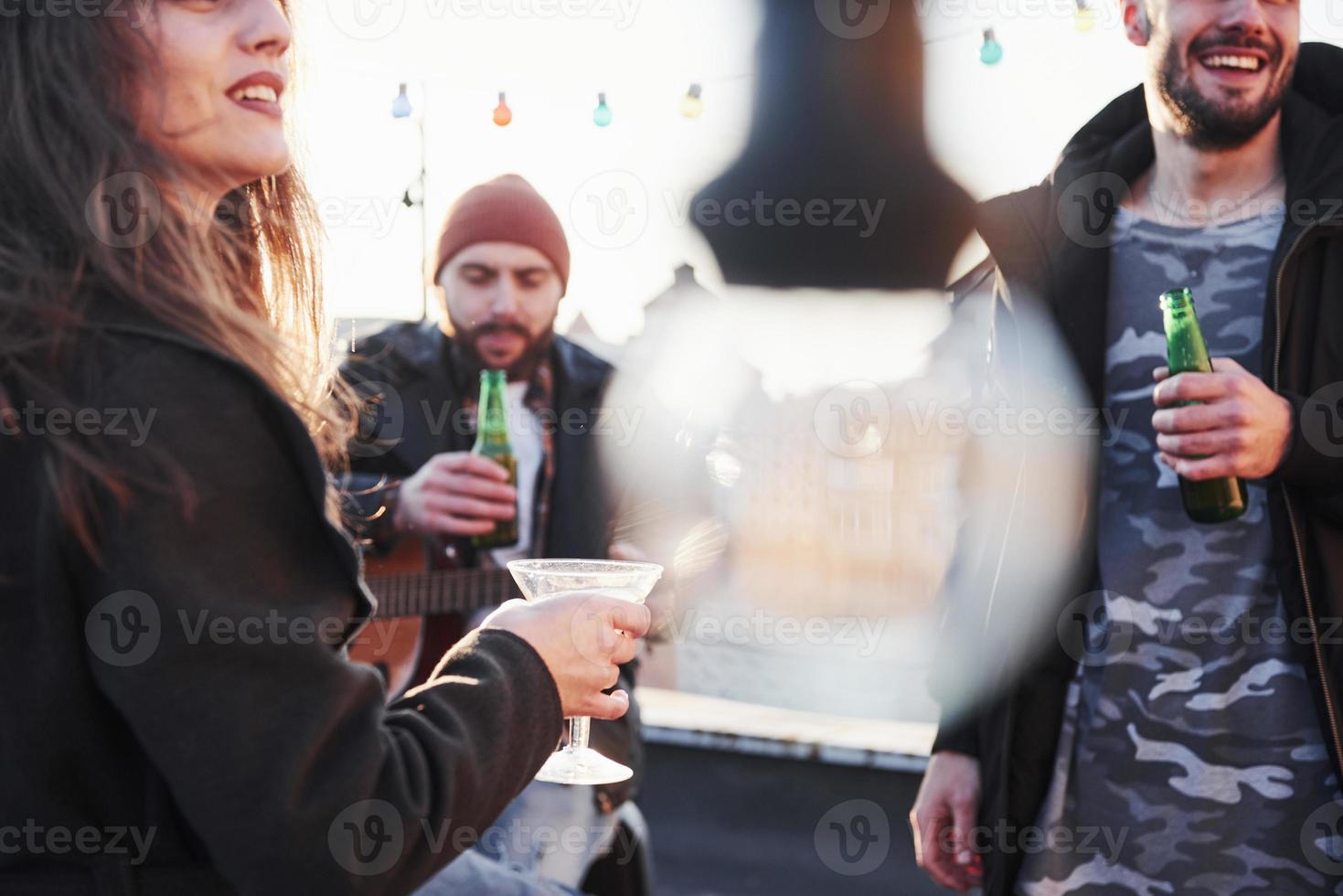 Three friends with alcohol and acoustic guitar. Blurred bulb in centre of the photo