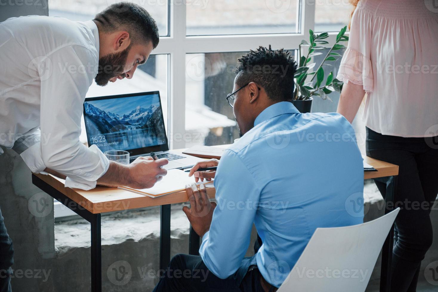 Back view. Office workers loaded with work and writing routine reports photo