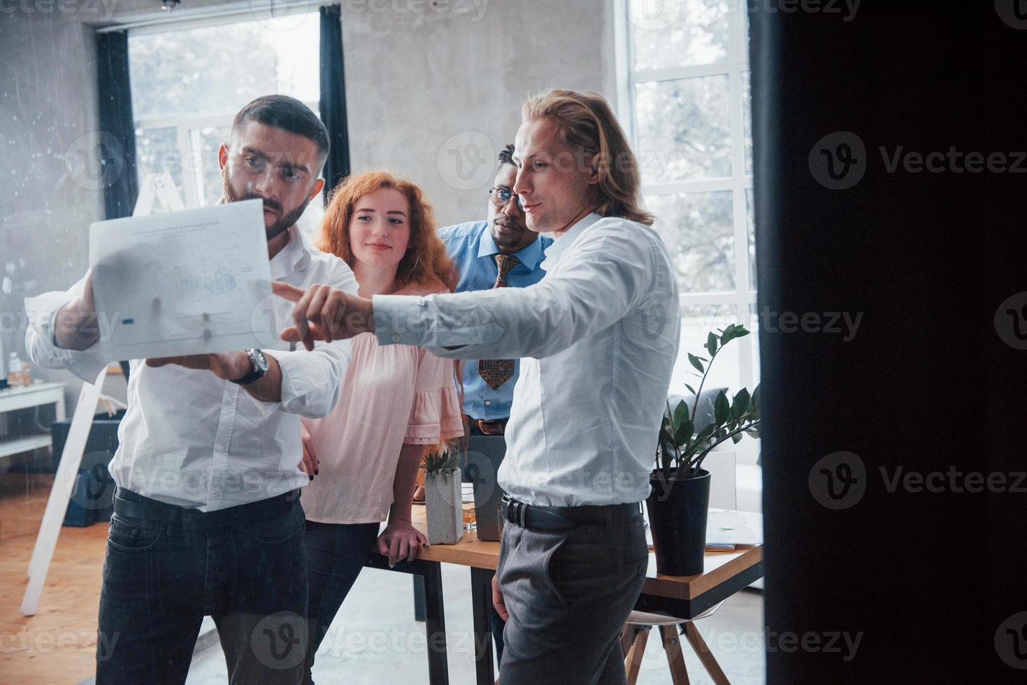 Feeling satisfied. Young multiracial team in official wear at office looking at price list photo