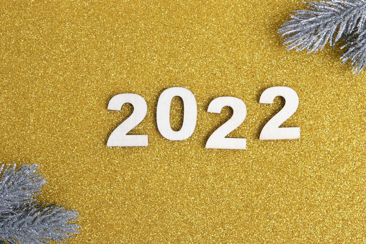 Wooden numbers new year 2022 on golden glitter background photo