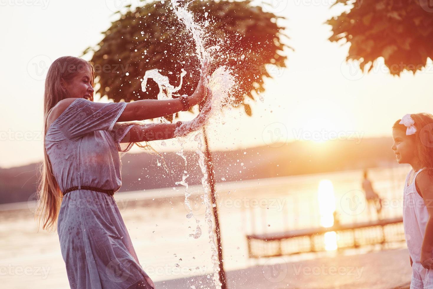 el agua es poder. en un día caluroso y soleado, la madre y su hija deciden usar la fuente para refrescarse y divertirse con ella foto
