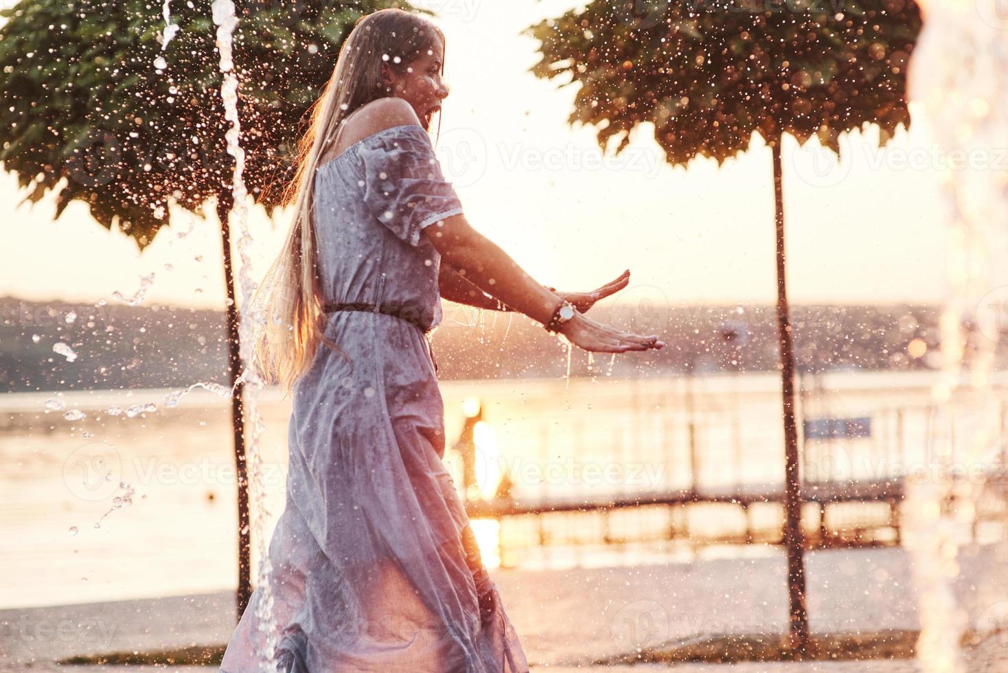 Feeling enexpected. Wet adult woman enjoying cooling by the water at hot day photo