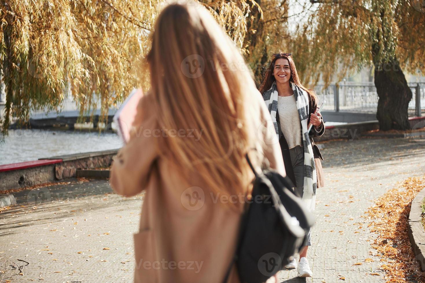 dos jóvenes amigos están felices de conocerse en el parque después de estudiar foto