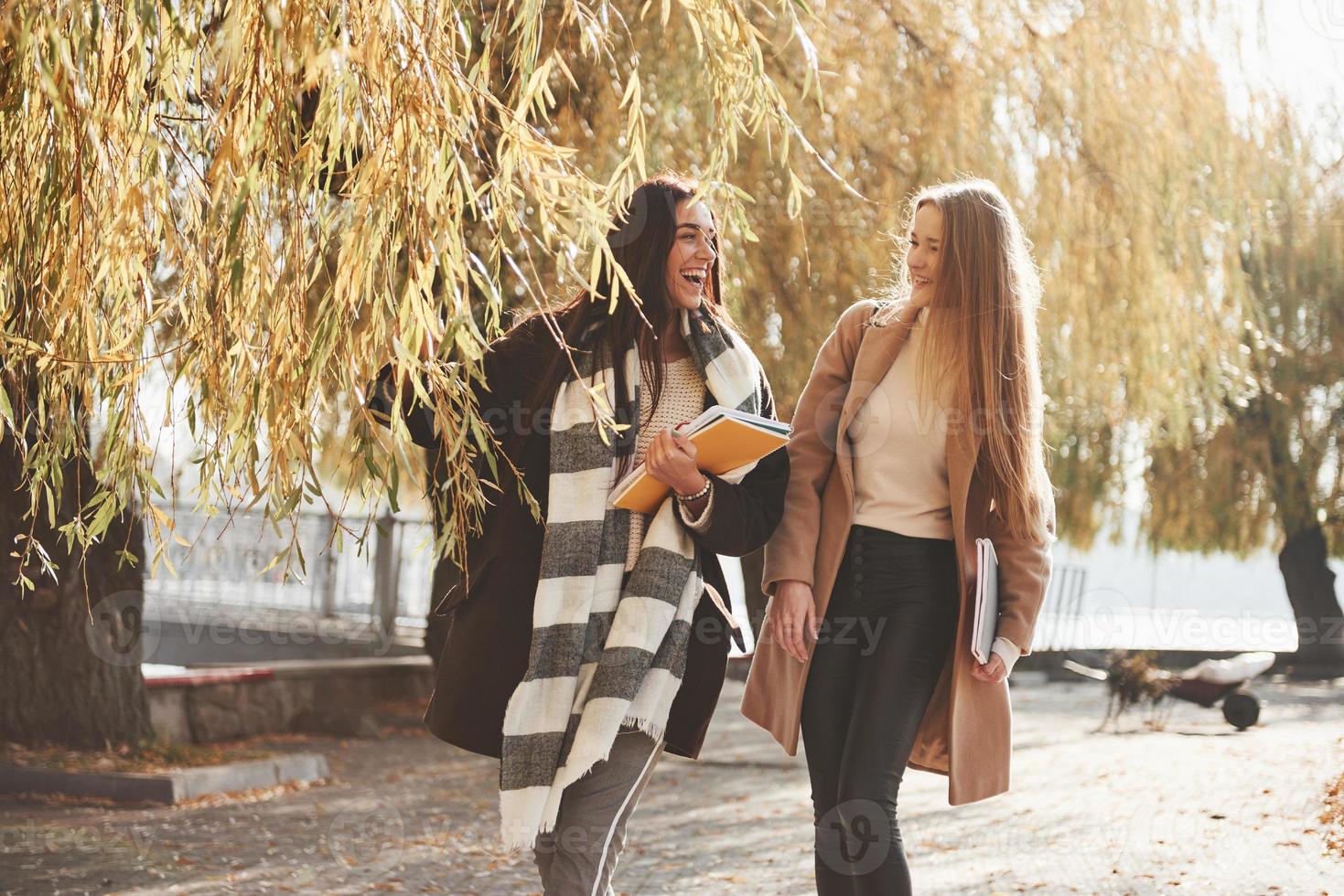 Relaxed atmosphere. Female friends have a walk through the beautiful autumn park photo