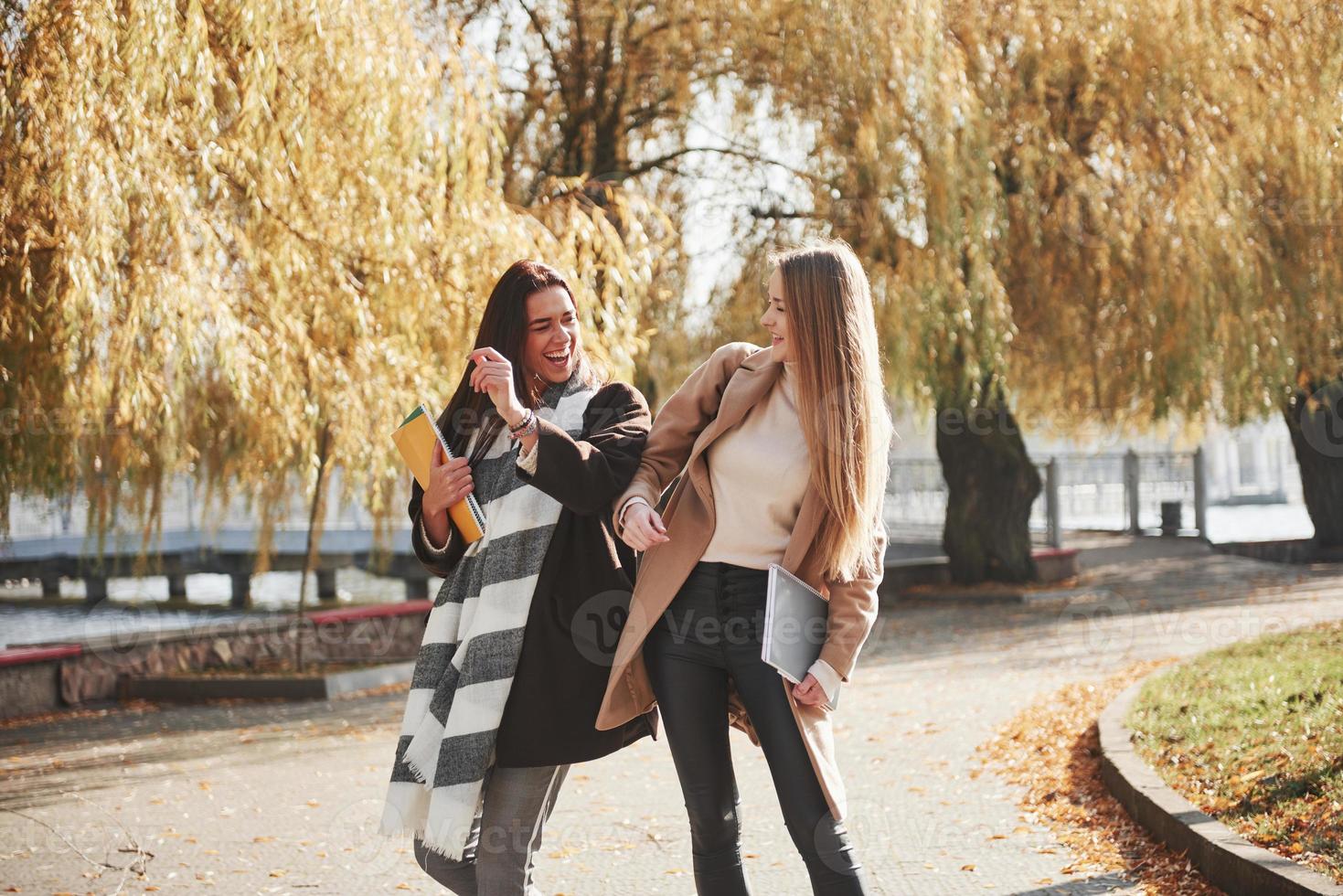 Friendly gesture between these two young and beautiful students in the autumn park photo