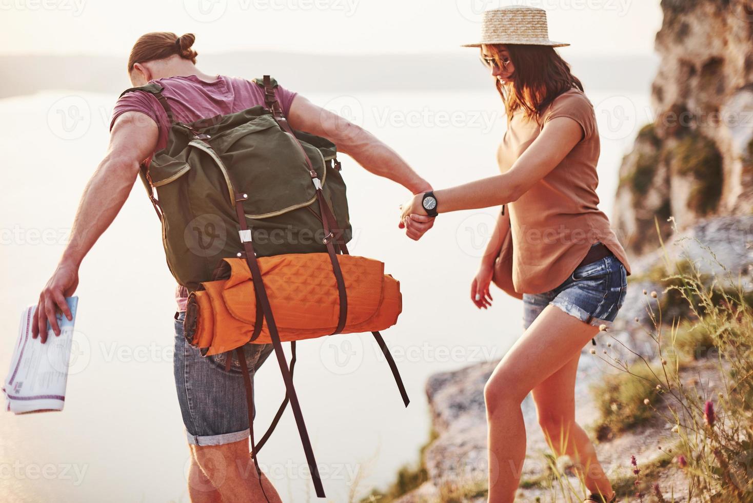 cuesta abajo extrema. pareja joven ha decidido pasar sus vacaciones de forma activa en el borde de la hermosa roca con el lago al fondo foto